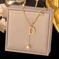 Detail of gold letter D pendant necklace with geometric cube on champagne jewelry box - Letter D-Gold