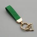 Green suede leather keychain with gold metal hardware and D-ring on grey background - Green Gold