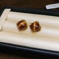 Close-up of vintage gold oval earrings with amber tiger eye stone on silk lining - Brown