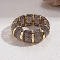 Macro shot of chunky brown glitter acrylic links with gold metal spacers on stretch bracelet - Gray