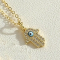 Macro shot of gold Hamsa hand pendant with sparkling zircons and blue evil eye detail - Black Palm Type 1
