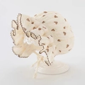 Detail of baby bonnet with brown heart patterns and layered ruffled edges in soft cream - Khaki Heart