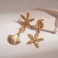 Macro detail of asymmetric golden starfish and seashell earrings with metallic texture - Gold / Gold