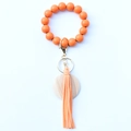 Détail du bracelet porte-clés à perles orange avec breloque en bois et gland en cuir - Orange Cayenne