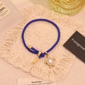 Dettaglio del bracciale intrecciato blu con ciondolo a tartaruga dorata e chiusura a scorrimento - Perla Sintetica
