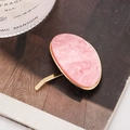 Gancho ovalado de mármol rosa con borde metálico dorado sobre superficie madera - Rosa