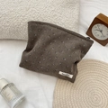 Detailopname van corduroy make-uptas met bloemenprint en label op zacht bed - Bruin