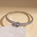 Detailed macro view of silver horseshoe bangle with pave diamonds on stone background - Silver