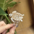 Macro detail of a small acetate sea turtle hair claw clip with golden shell patterns - Coconut White Marble - Small (Approx. 4.5cm)