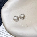 Makroaufnahme von silbernen C-förmigen Ohrringen auf Keramikschale mit weichem Licht - Runder Creolen Mit Diamantschliff / Silber