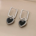 Macro shot of silver heart drop earrings with black enamel and textured metal detailing - Steel-Black