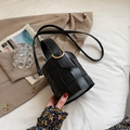 Schwarze gewebte Beuteltasche aus Leder mit goldenen Ringen auf kariertem Sakko - Schwarz