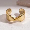 Detail van gouden golvende manchetarmband met gepolijste afwerking op wit natuursteen - Wave Open Stijl / Goud