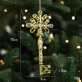 Golden vintage key Christmas ornament with embossed patterns hanging on a tree branch - Key Style
