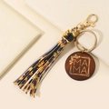 MAMA wooden charm keychain with golden clasp and sunflower pattern tassel on beige background - Sunflower