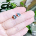 Gros plan de boucles d'oreilles en cristal bleu clair taille poire entre les doigts - goutte / Bleu Mer Clair