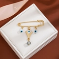 Detail showing golden evil eye brooch with crystal pendant and tassel in white gift box - Triangle Crystal Style (Z69)