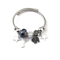 Detail of a silver twisted bangle with star, diamond key, and elephant pendants - Black