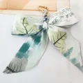 Close-up of camellia silk bow keychain with golden metal ring and forest pattern print - No.9 (Light Green Leaves)