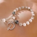 Detail of beaded bracelet with silver dragon pendant and white cat-eye gemstones - Silver