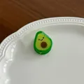 Close-up of a cute cartoon avocado hair clip on a white ceramic shell plate - Avocado