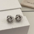 Macro shot of silver twisted knot stud earrings with a polished mirror finish detail - Silver Knot Studs