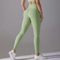 Detail of high waisted yoga pants in light green featuring v-shape lifting seam and sleek fabric - S / Avocado Green