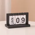 Modern black minimalist flip calendar with white monthly and daily cards on a white desk - Black