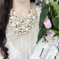 Statement layered white pearl bib necklace with long tassels on a model for bridal style - Luxury Bib-Style Statement Pearl Fringe Necklace