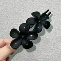 Gros plan sur l'élégante pince à cheveux en acrylique noir mat avec fleurs et strass - Noir Classique