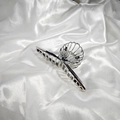 Detail of silver alloy hair claw clip with hollow shell design on white silk background - Triple Shell Claw