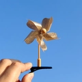 Gros plan d'une pince à cheveux moulin à vent à paillettes dorées sur fond de ciel bleu - 5 Feuilles/Or