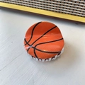 Detailed view of the orange basketball hair claw clip with black texture on white wood - Large Basketball (7.9cm)