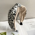 Close-up of leopard print wide headband with beige lining resting on an open book - Leopard White