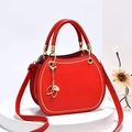 Bolso de mano circular rojo elegante con colgante de hoja dorada en podio blanco - Rojo