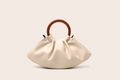 Detail of ruched cream cloud bag with brown round handle on minimalist background - Off White