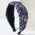 Dettaglio del tessuto del cerchietto Mardi Gras con motivi di maschere e pois bianchi - Viola