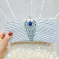 Silver pleated evening clutch bag featuring a detailed blue crystal peacock ornament - Silver
