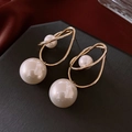 Detailed close-up of geometric gold metal earrings with dual pearls on dark background - Gold Twisted Loop Double Pearl Earrings