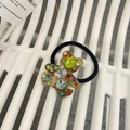 Detalle de una goma para el pelo con un oso de resina brillante y cristales de colores - Diadema De Oso Con Gemas De Color Verde Y Marrón