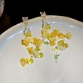 Detailansicht der handgefertigten Blumen-Ohrringe mit gelben Perlen und Kristallen - Grün