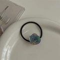 Detailed shot of gradient resin rose flower hair tie on a white ceramic plate - Rainbow