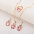 Detailsicht des goldenen Schmucksets mit rosa Herzkristallen auf weißem Stoffhintergrund - 3-teiliges Set / Herz-LOVE Rosa