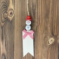Houten sneeuwpop hanger met rode hoed en geruite strik op rustieke houten achtergrond - Rode Sneeuwpop Label