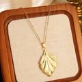 Golden ginkgo leaf pendant necklace with delicate chain on a wooden jewelry display - Gold Vintage Ginkgo Leaf Pendant Necklace