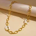 Detailweergave van een vintage gouden ketting met witte emaille schakels op een display - Ketting - Goud