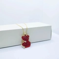 Golden necklace featuring a red bear pendant with gold stars on a white stand - Necklace / Red
