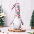 Detail van kerstkabouter met sneeuwvlokmuts op boomstam met feestelijke dennenappels - Cyaan