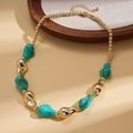 Dettaglio di perline in resina verde irregolari e perline metalliche dorate in una collana - Blu