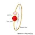 Detail view of gold stainless steel open bangle featuring pink and red square glass stones - Gold Red Stone